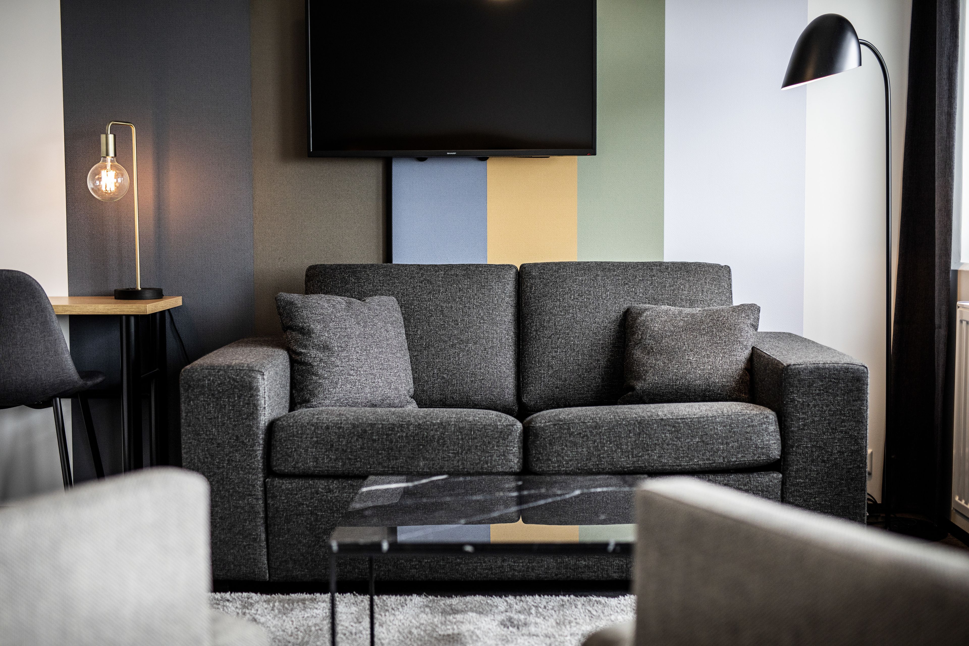 Un salon moderne avec un canapé gris, une table basse et un lampadaire.