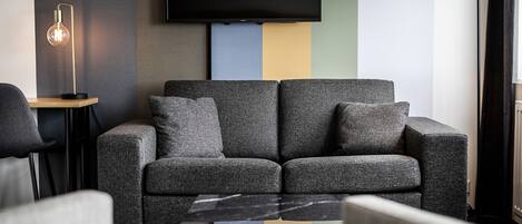 Un salon moderne avec un canapé gris, une table basse et un lampadaire.