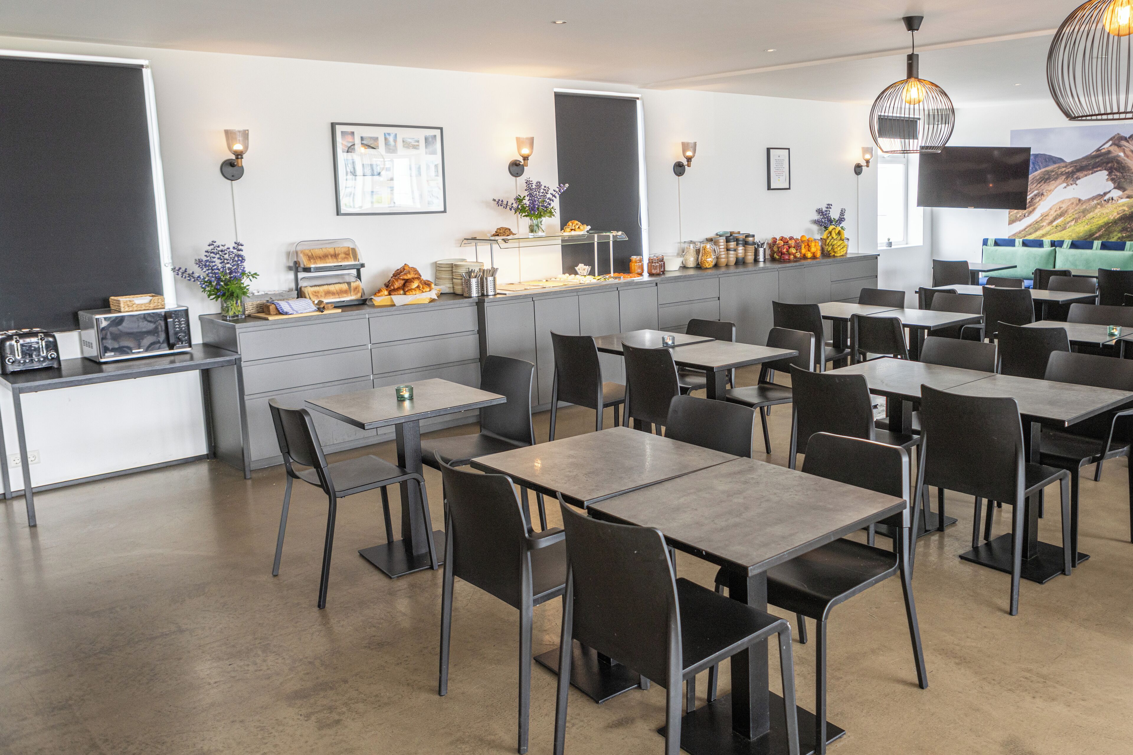 A modern restaurant with a counter, tables, chairs, and a flat-screen TV.