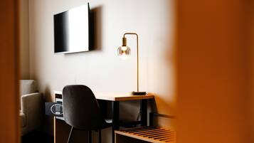 Un escritorio moderno con una silla, una lámpara de escritorio y un televisor de pantalla plana montado en la pared.