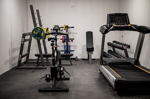 Una palestra con tapis roulant, panca per pesi e diverse attrezzature per esercizi.