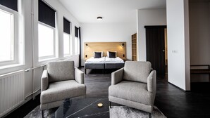 A modern hotel room with a large bed, two armchairs, a coffee table, and a view of the city. - 201 Hotel (Kópavogur)