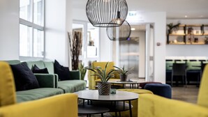 A modern lounge area with yellow armchairs, a round table, and a potted plant. - 201 Hotel (Kópavogur)