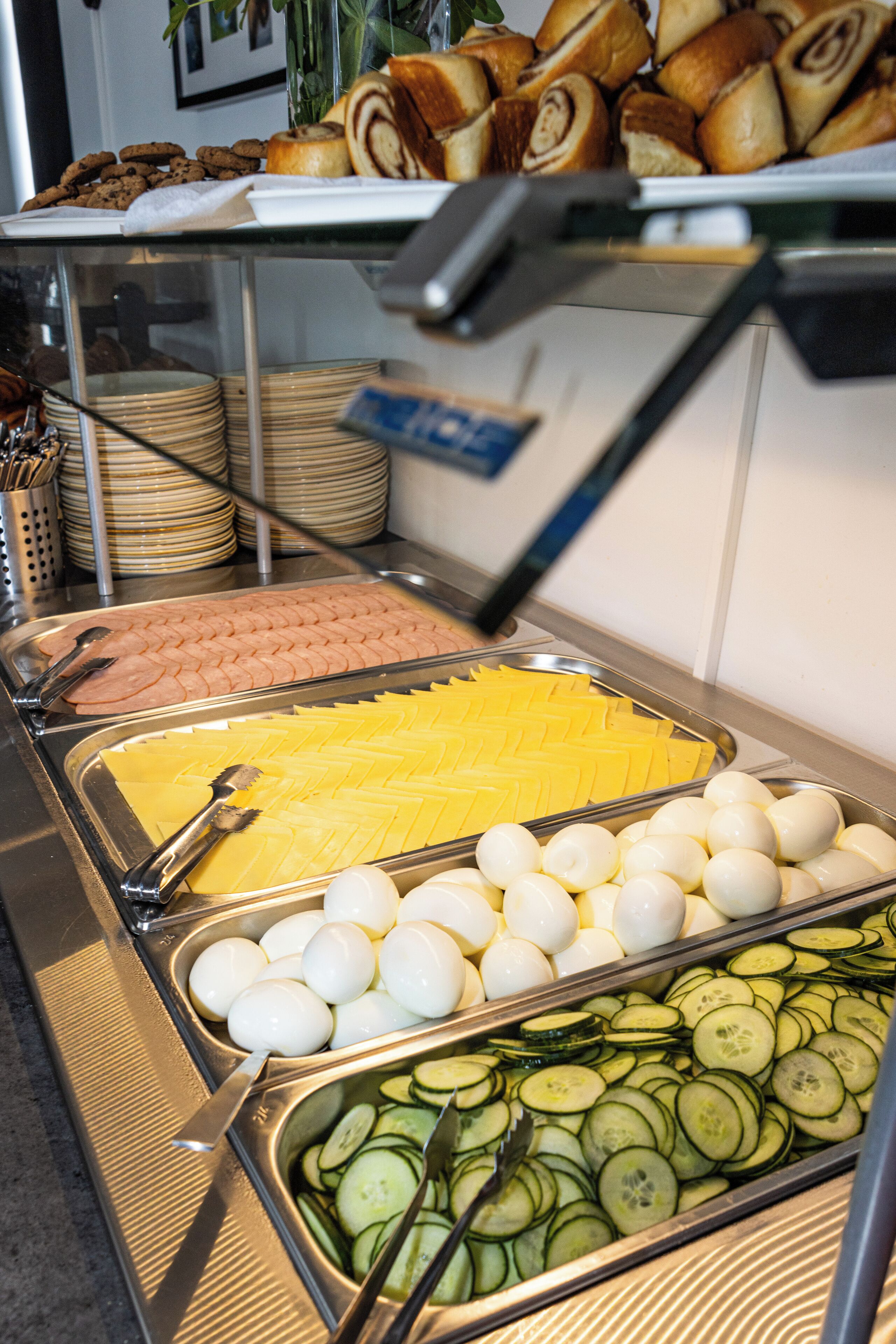 Un buffet proposant une variété d’aliments, notamment du pain tranché, des œufs et des concombres.