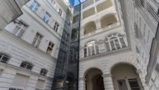Un edificio de varios pisos con arquitectura clásica, que presenta arcos en puertas y ventanas.