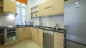 Una cocina moderna con electrodomésticos de acero inoxidable, armarios de madera y un ventanal con persianas.