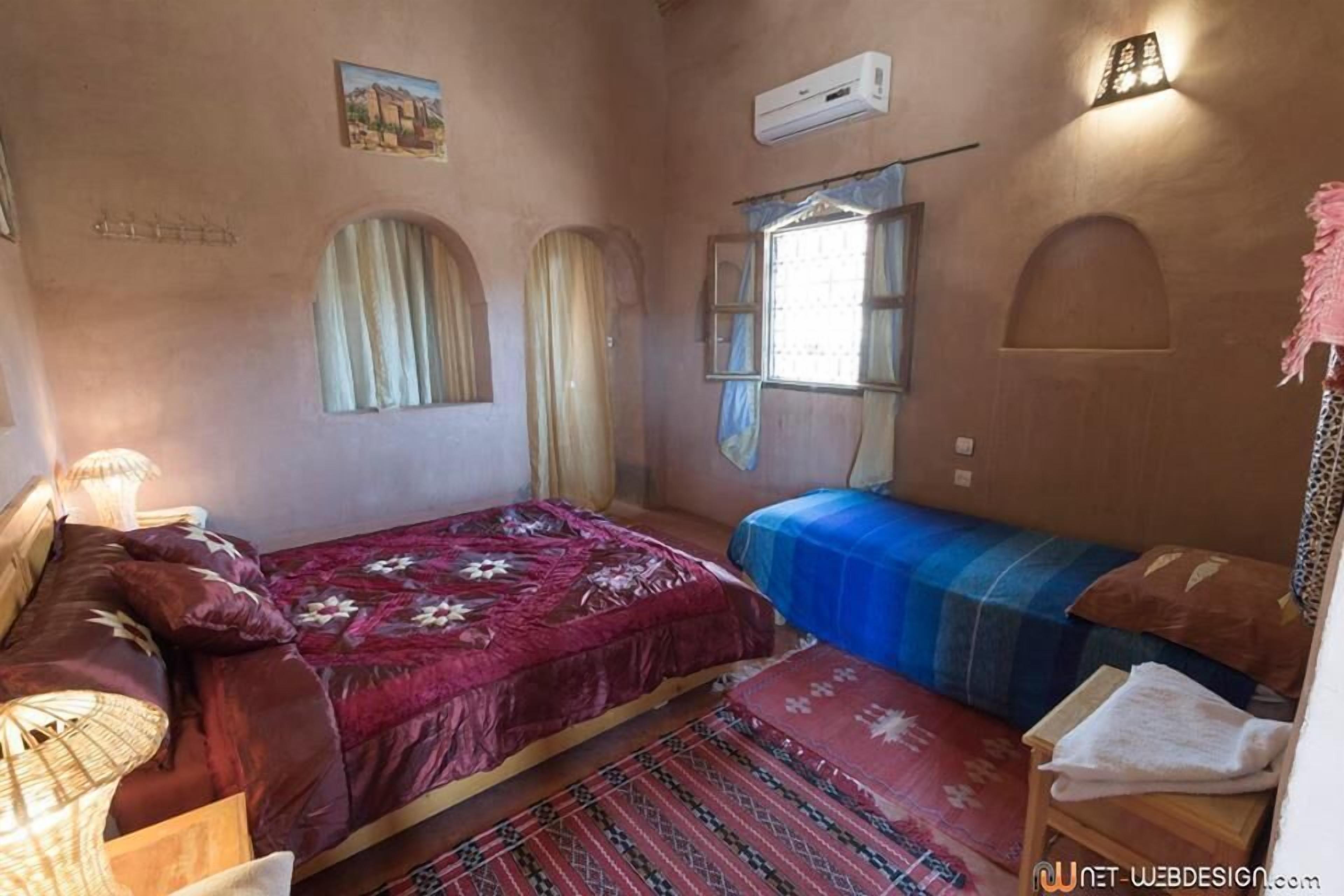Una habitación con una cama, un sofá, una mesita y un ventanal con cortinas.
