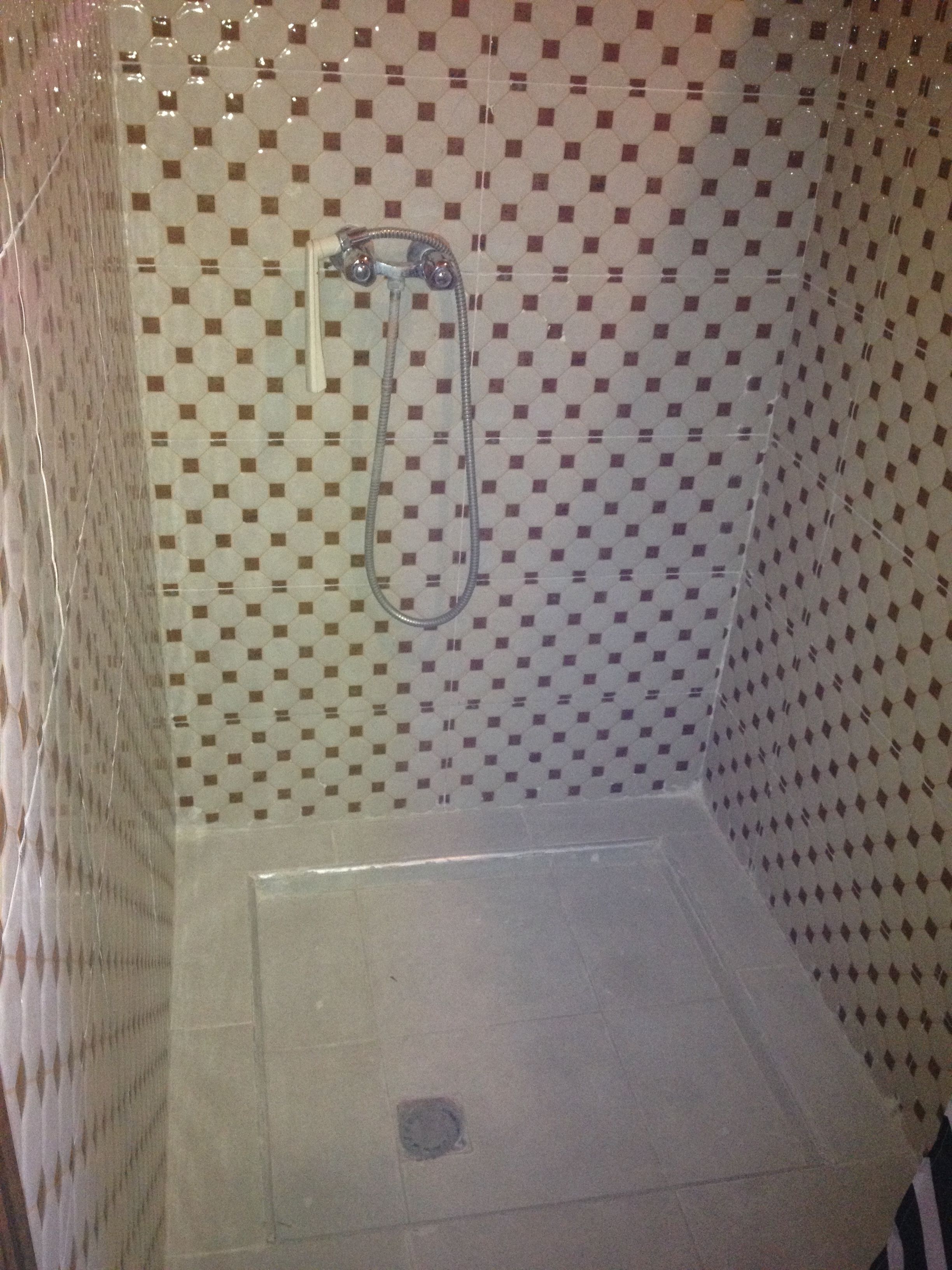 Una ducha con pared de azulejos y un cabezal.