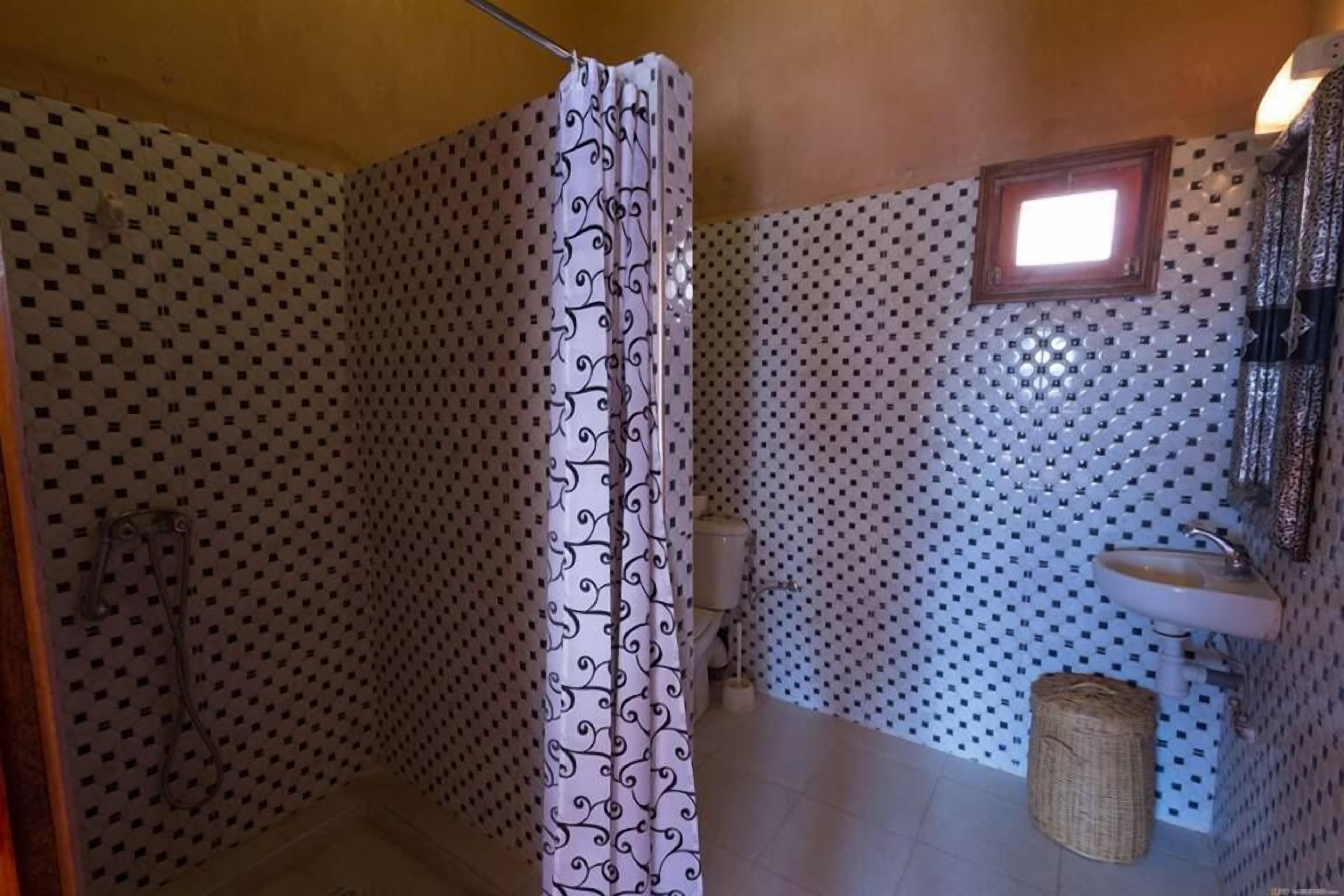 A bathroom with a shower curtain, a sink, and a toilet.