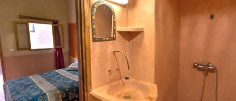 A bathroom with a sink, mirror, and shower.