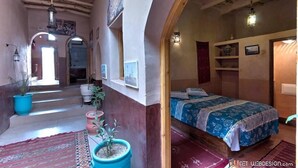 Una habitación acogedora con una cama, una mesita pequeña y una planta en maceta.