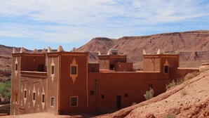 Un edificio tradicional marroquí con techo plano, varias ventanas pequeñas y fachada plana.