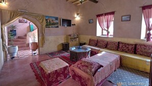 Una habitación acogedora con suelo de cuadros, un sofá, una mesita y una escalera que sube a otra zona.