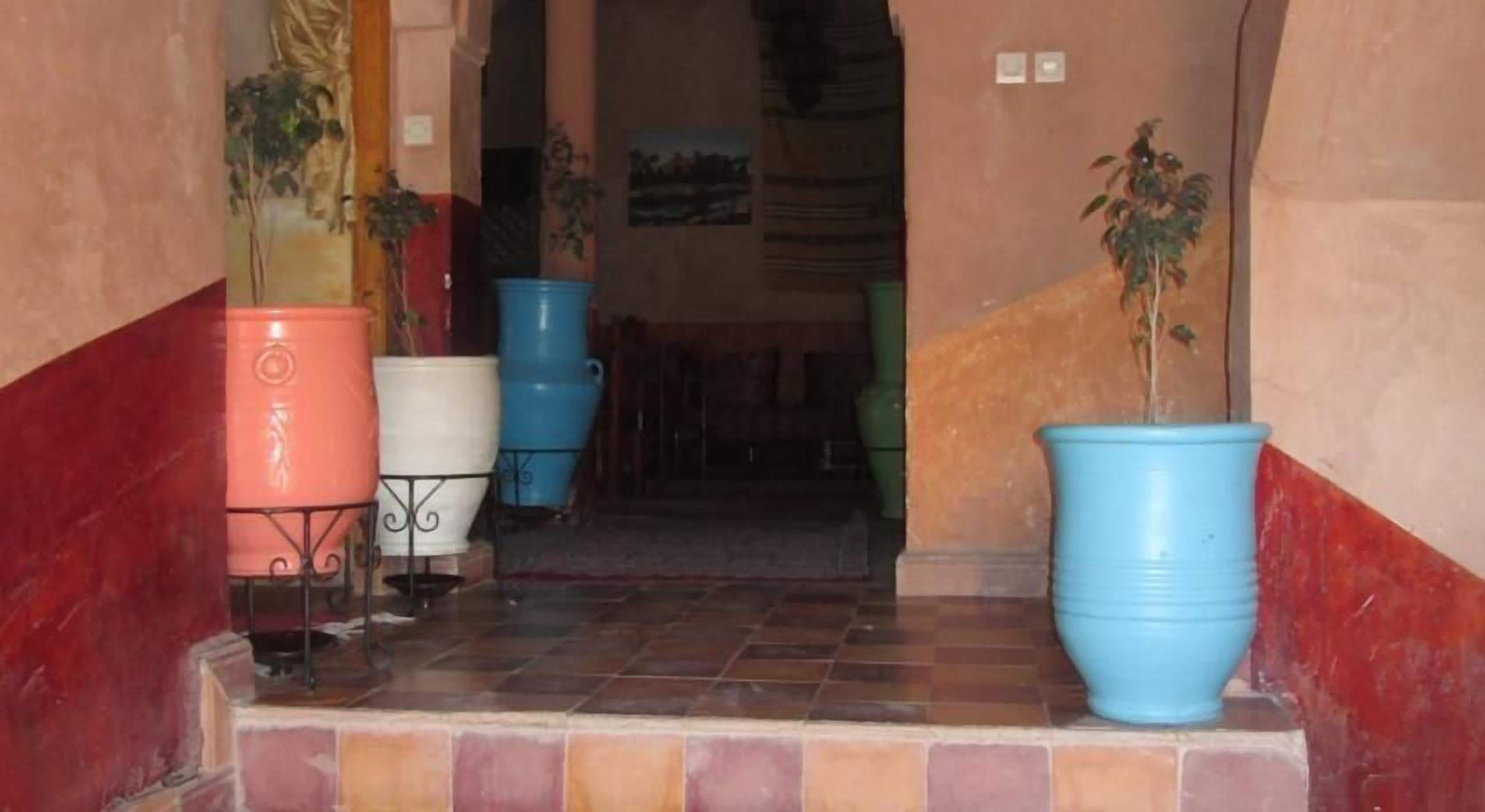 A hallway with tiled flooring and large potted plants.