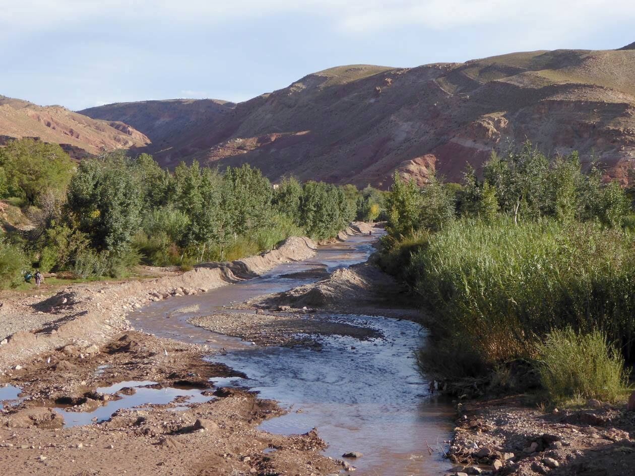 A natural landscape with a river, rocky terrain, and sparse vegetation.