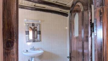 A wooden door leading to a bathroom with a white sink and a towel rack.