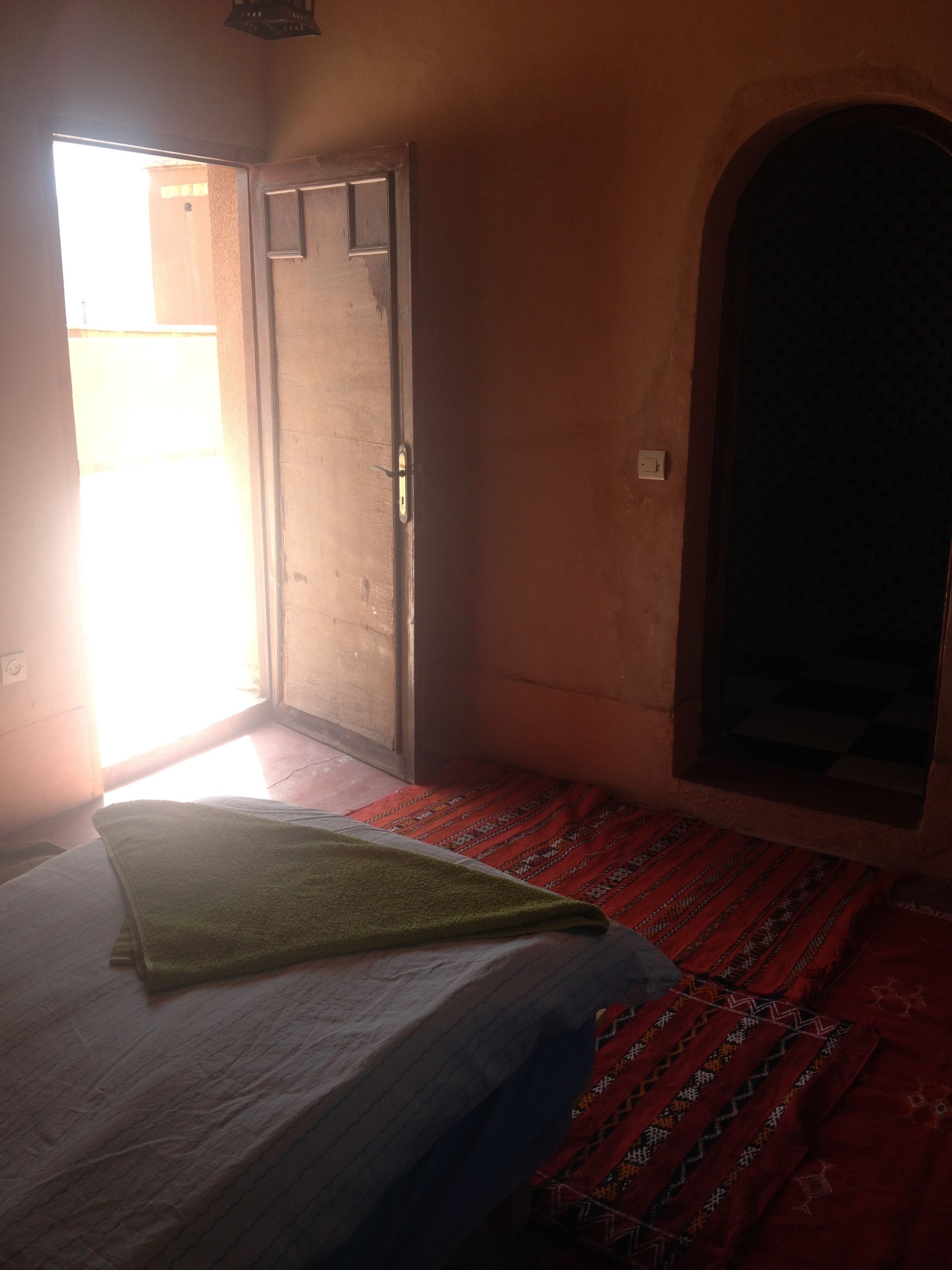 Una habitació amb un llit, una porta i una finestra.