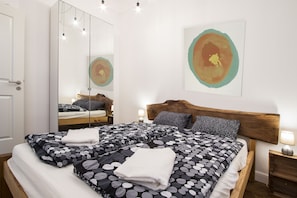 A double bed with a polka dot bedspread, a wooden headboard, bedside lamps, and a large mirror.