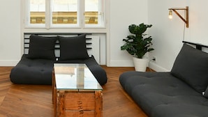 A modern living room with a sofa set, a glass-top coffee table, and a potted plant.