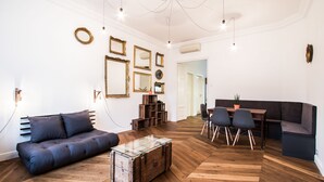 A modern living room with a sofa, a glass-top coffee table, and a dining area with a table and chairs.