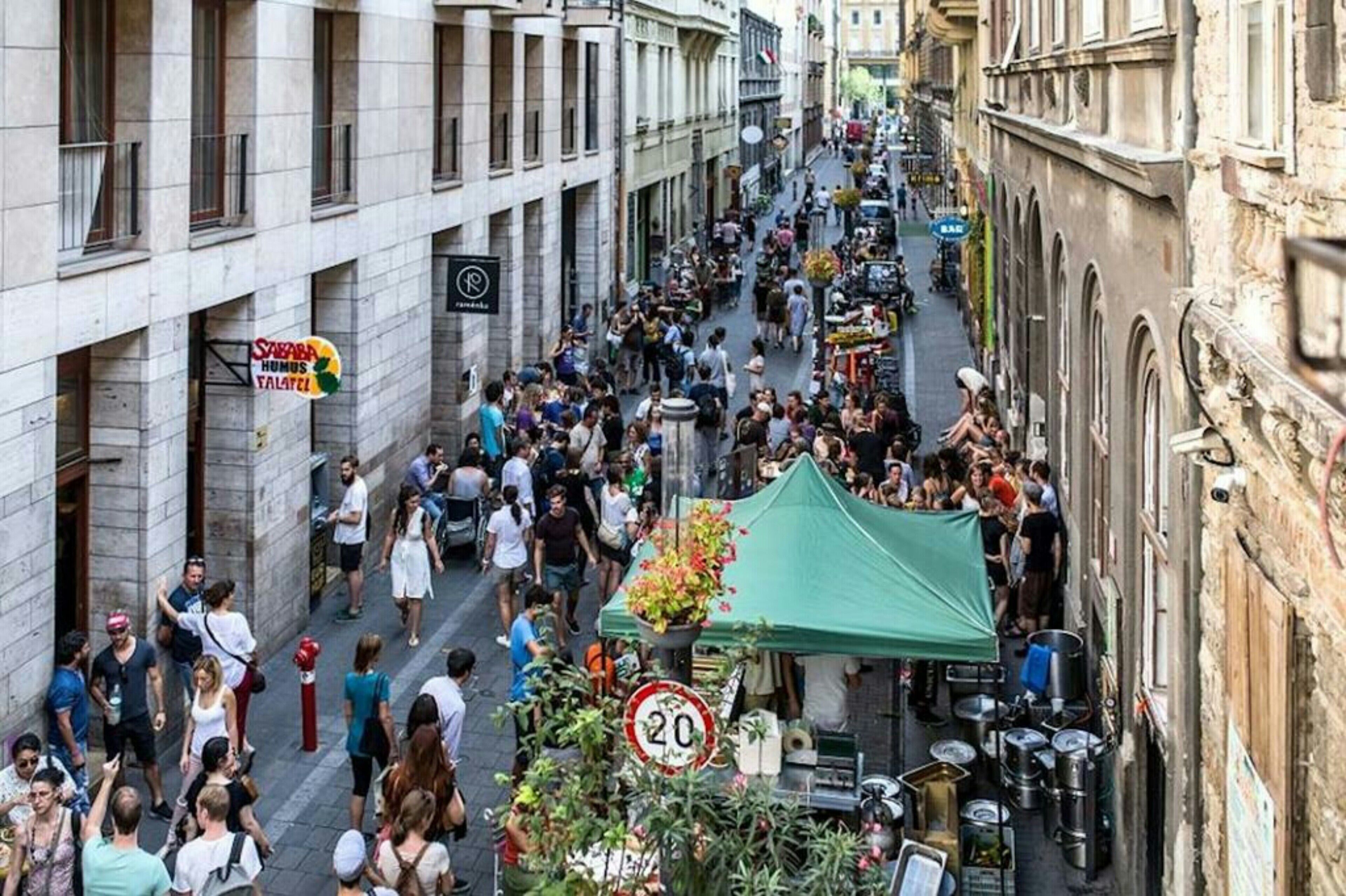 A crowded street with people walking and vendors selling goods.