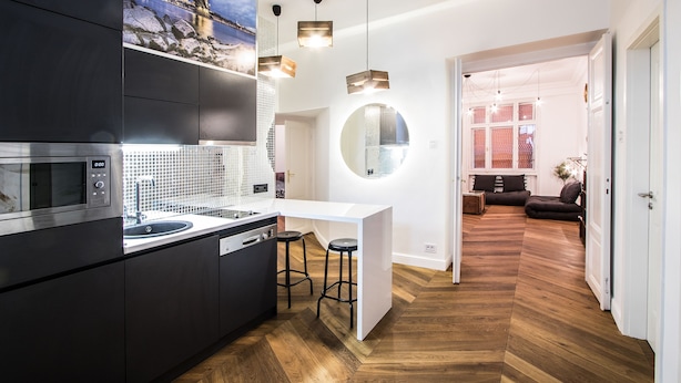A modern kitchen with a built-in microwave, a sink, and a dining area with stools.