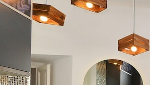 A modern interior with wooden pendant lights, a tiled backsplash, and a circular mirror.