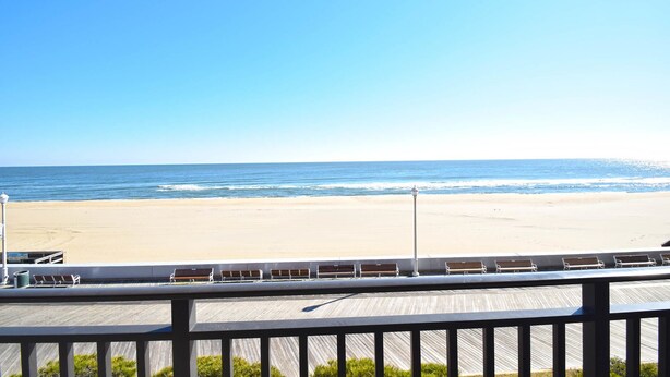A beach view from a balcony with a wooden deck and benches. - Ocean Hideaway 202 (Ocean City)