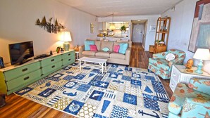 A living room with a sofa, a coffee table, a TV, and a patterned rug. - Ocean Hideaway 202 (Ocean City)