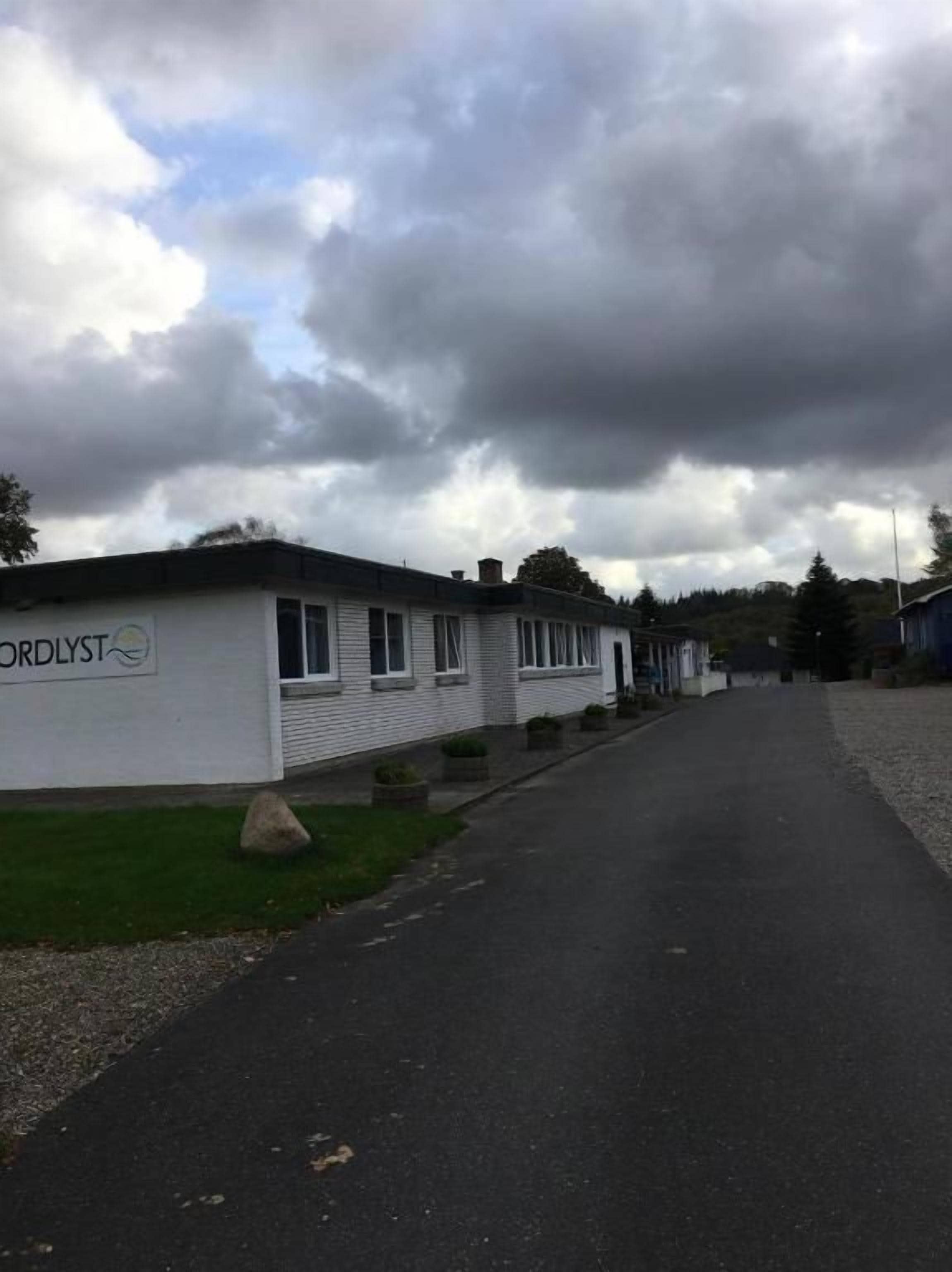 A row of white mobile homes with the name 'CORDLYST' on the side, a paved driveway, and a grassy area in front.
