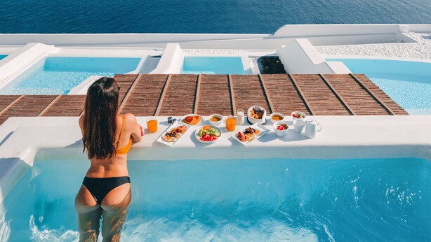 Eine Frau in einem Pool, im Hintergrund ein Tisch mit Essen und Getränken.