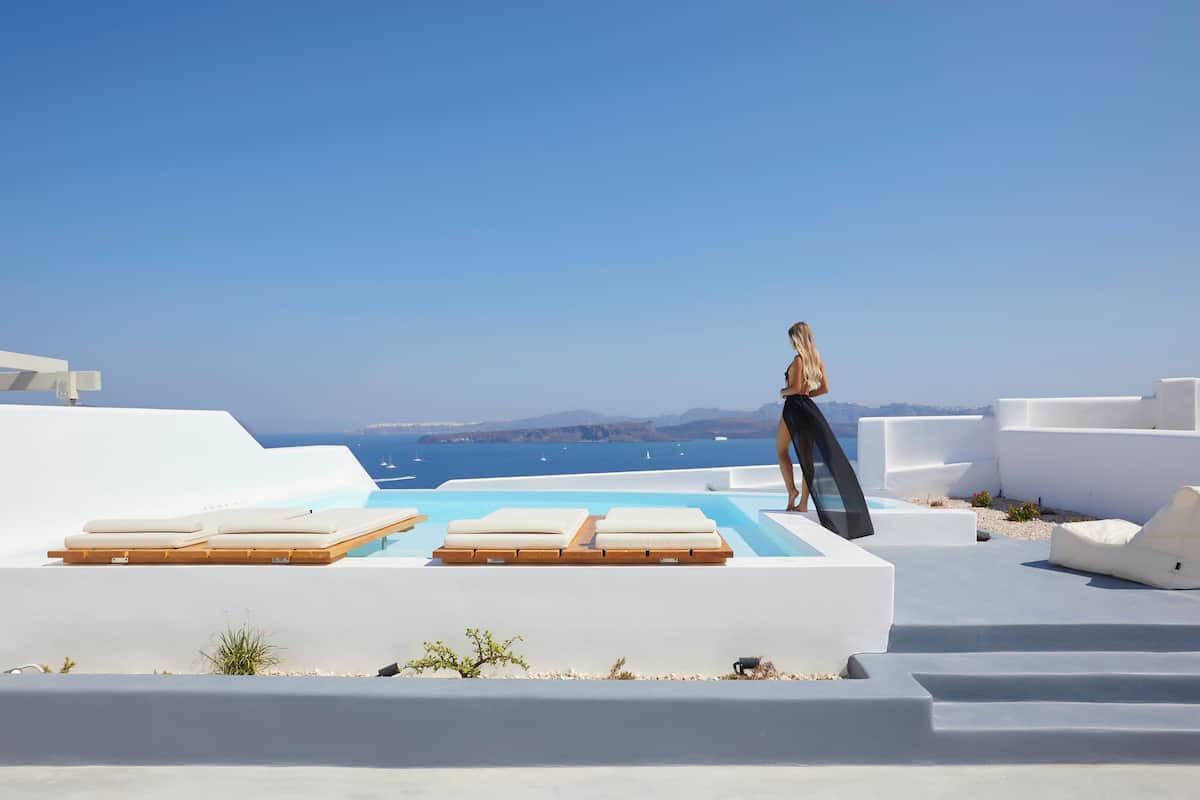 Un espace piscine extérieur moderne, doté de chaises longues et offrant une vue dégagée sur la mer.