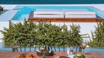 A dining table with a view of a pool and mountains.