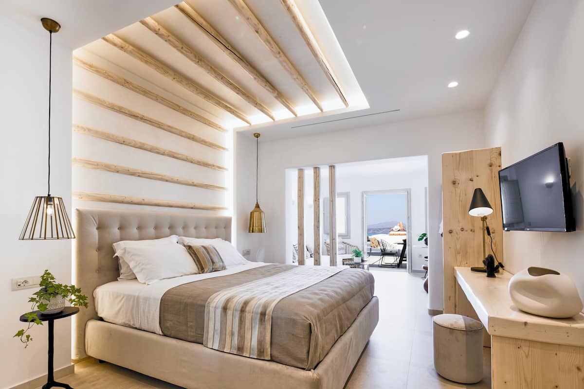 Une chambre moderne avec un grand lit, un bureau avec une télévision et une vue sur l’extérieur.