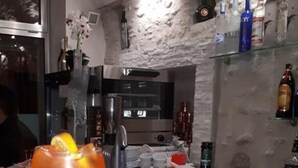 A bar area with a drink in a glass, bottles on shelves, and a menu on the counter. - Volì club Bed & Breakfast (Siderno)