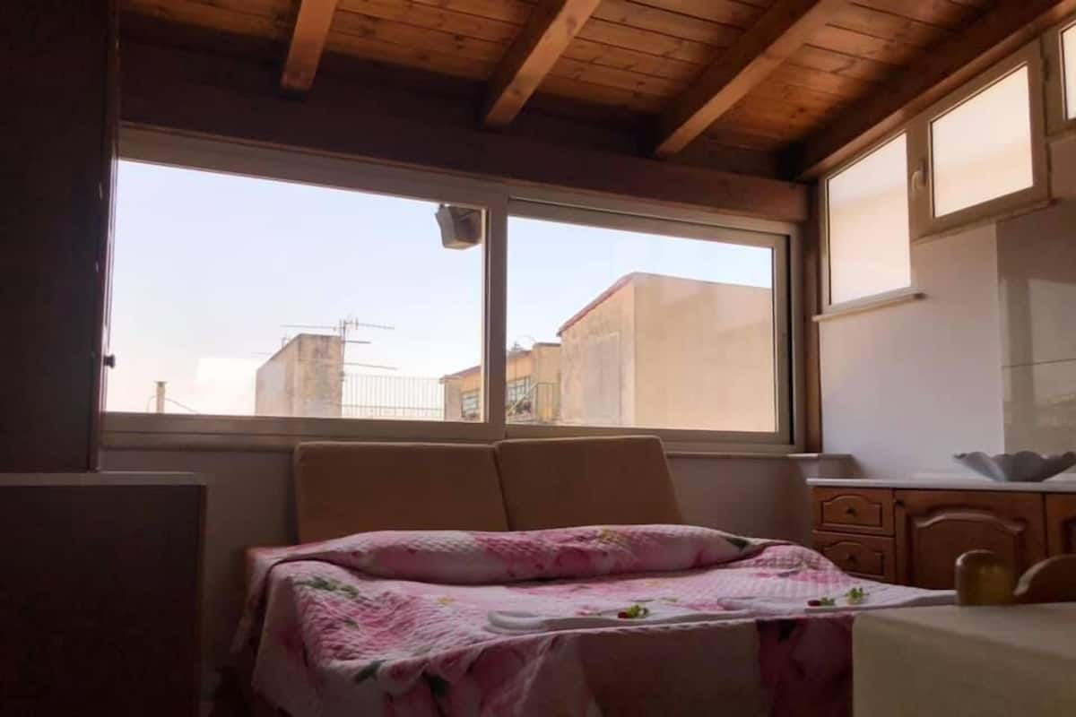 Une chambre à coucher avec un lit, une fenêtre et un plafond en bois.