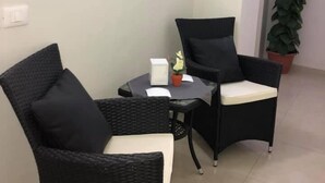 A room with two black wicker chairs, a small round table with a white object and a potted plant. - Volì club Bed & Breakfast (Siderno)
