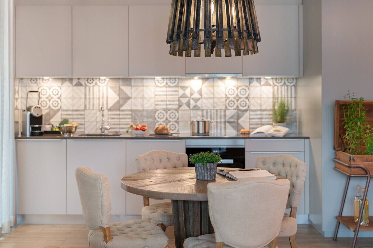 A modern kitchen with a central island, pendant lighting, and a patterned backsplash.
