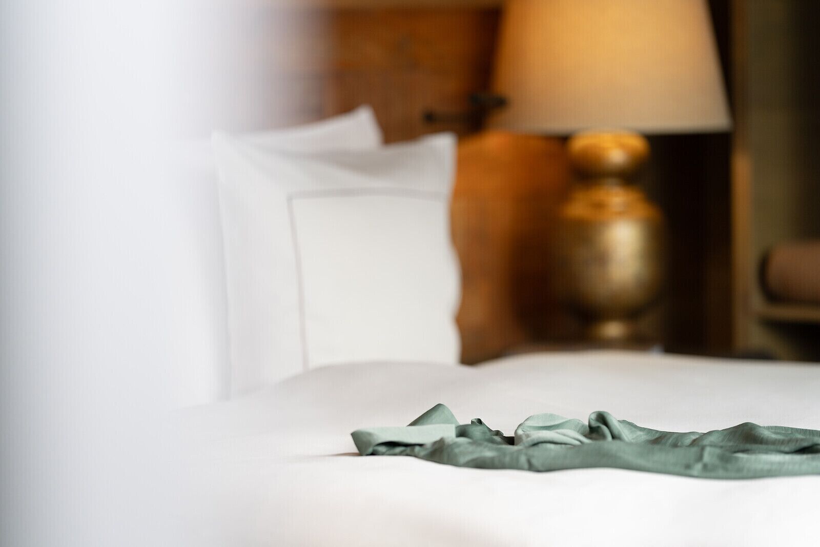 A bed with a white sheet and a green cloth.