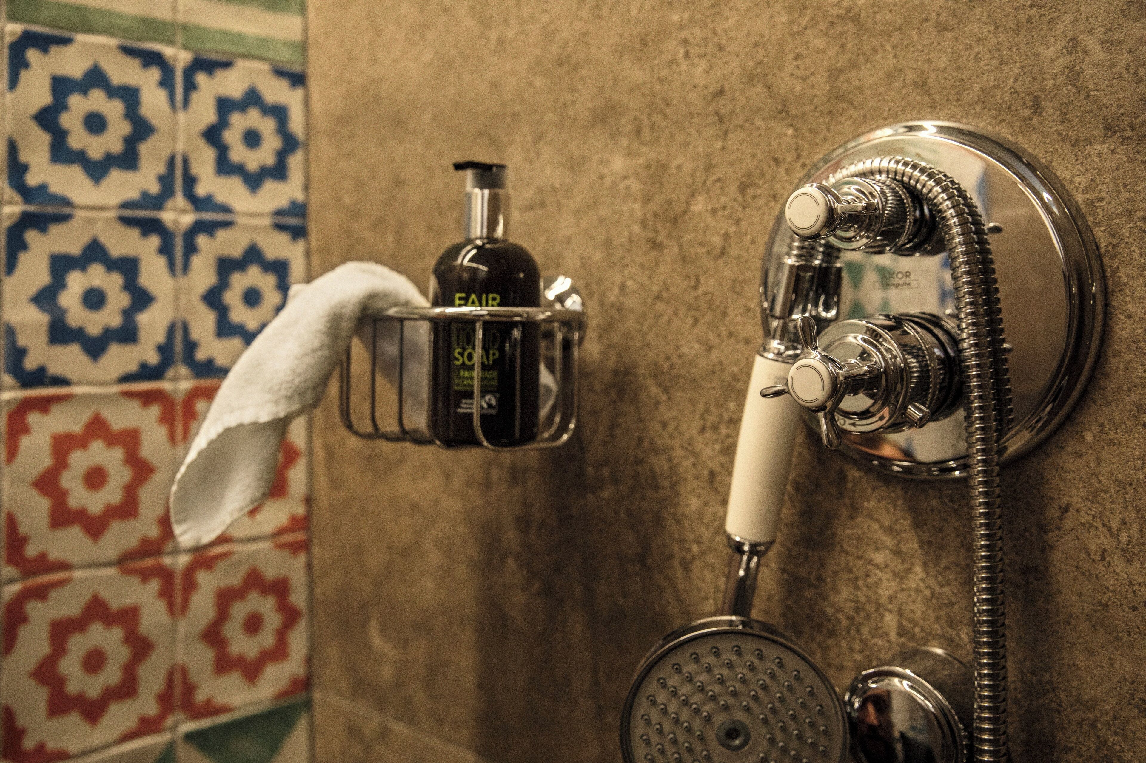 A bathroom with a shower, a towel rack, and a soap dispenser.