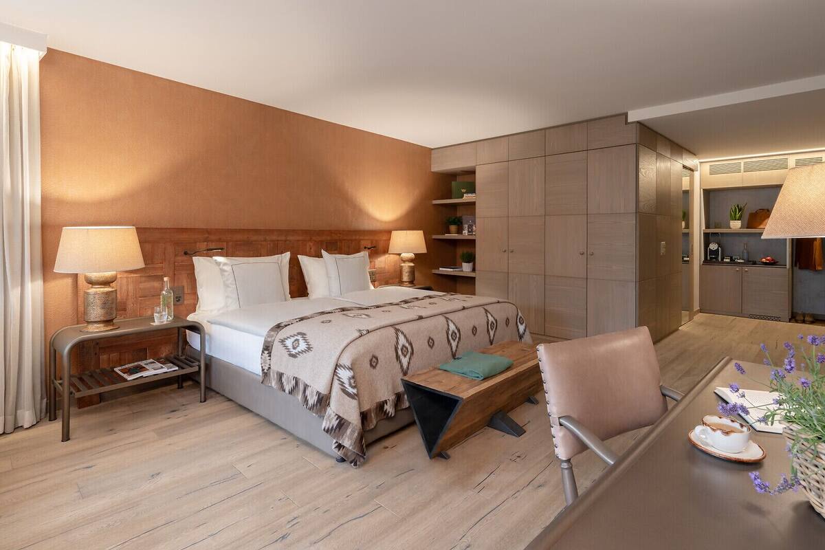 A hotel room with a bed, bedside tables, a desk, and a chair.