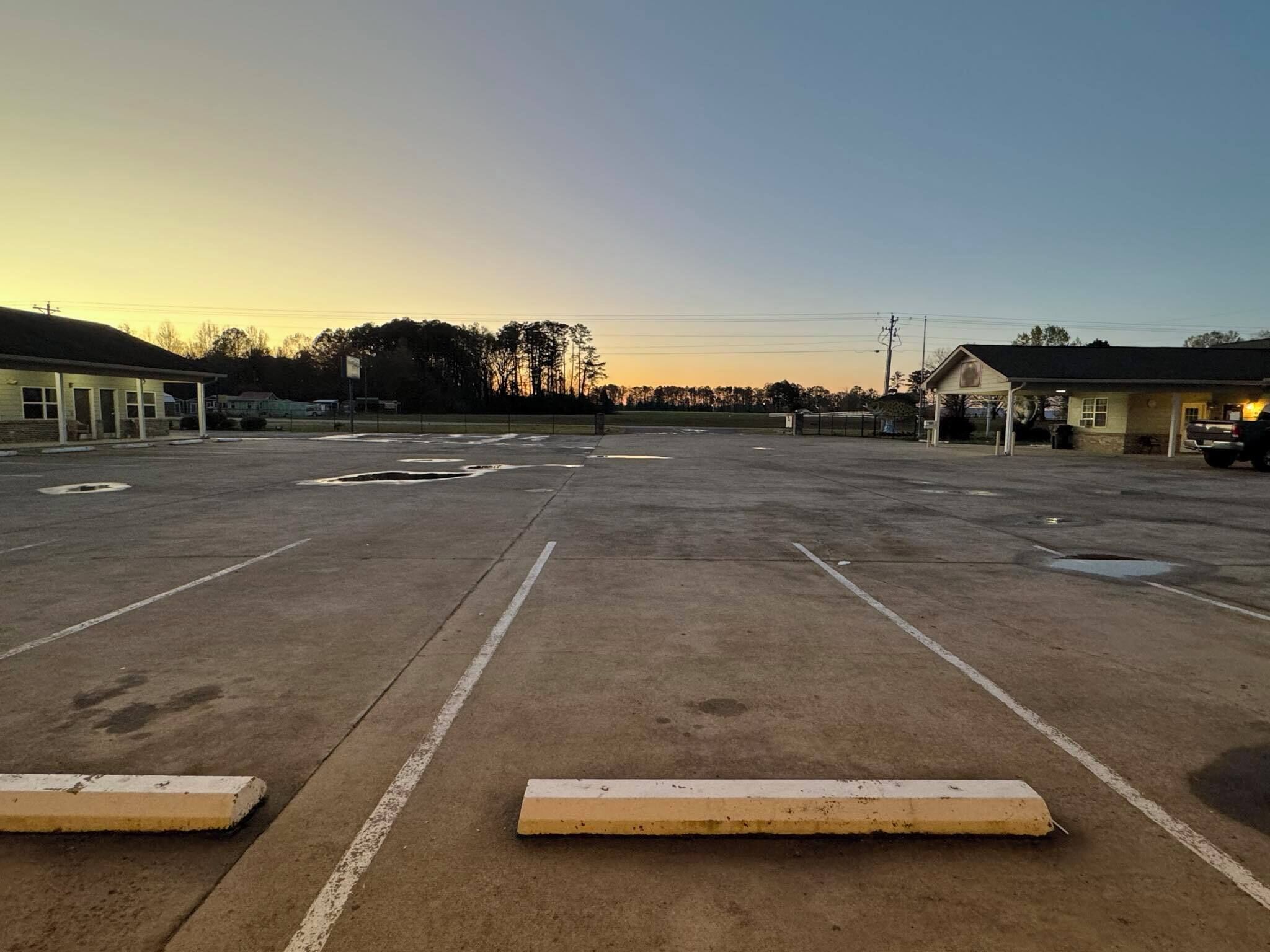 A large parking lot with marked parking spaces and a building in the background.