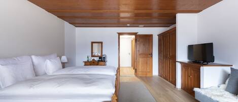 A bedroom with a wooden ceiling, a bed, a television on a stand, and a sofa.