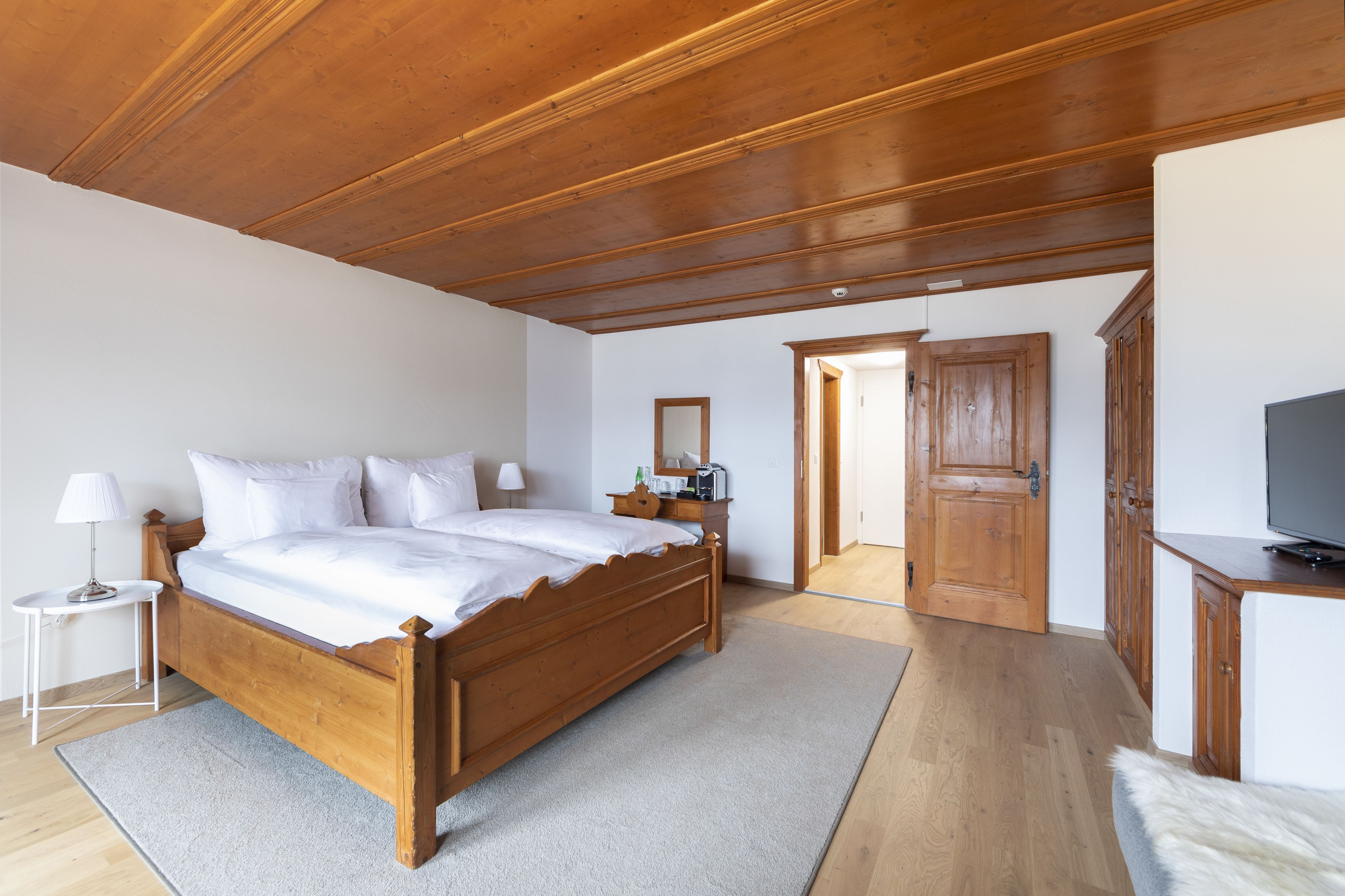 A bedroom with a wooden bed, a nightstand, a TV, and a wardrobe.