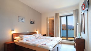 Un dormitorio con una cama grande, una mesita de noche, un aparador y vistas al exterior a través de una puerta corrediza.