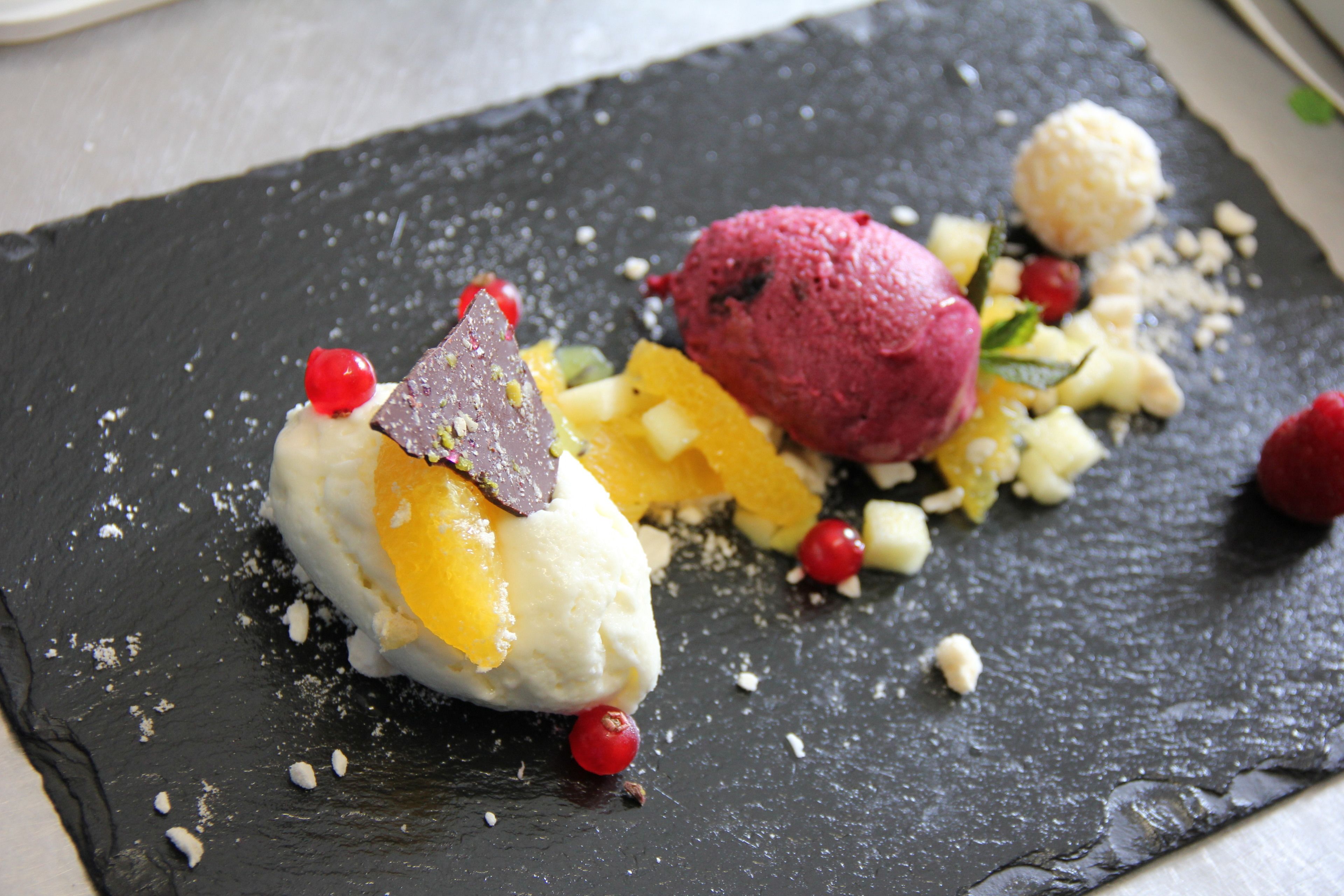 Un postre sobre un plato de pizarra con fruta y frutos secos.
