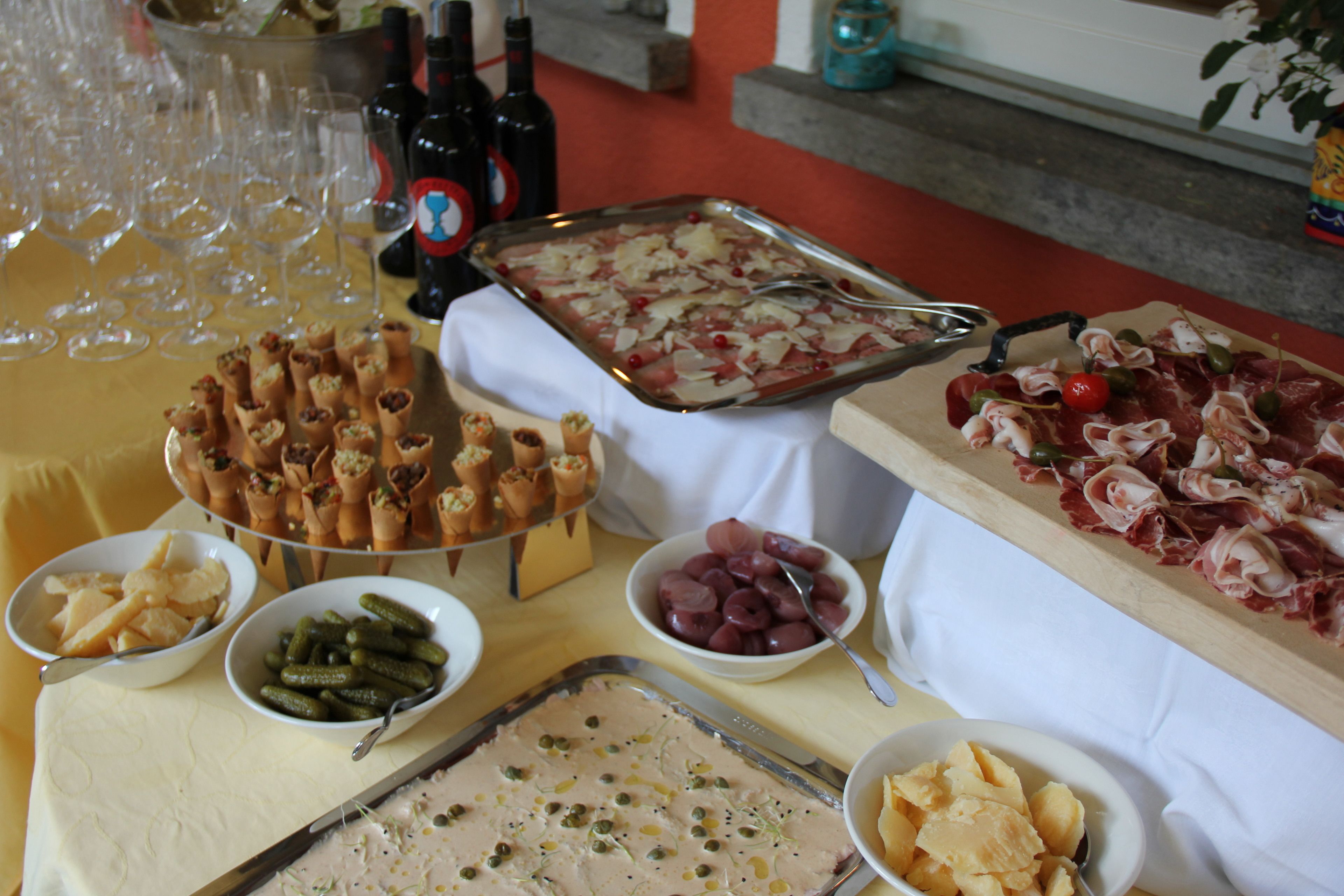 A buffet table with various food items, including a tray of meat, bowls of pickles, and a dish with olives.