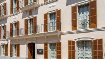 A multi-story building with balconies, wooden shutters, and a sign reading 'CAN RIBERA.'