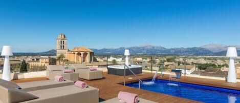 Una piscina al aire libre, sombrillas, sillones reclinables de piscina