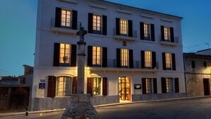 A multi-story building with a central entrance, large windows with shutters, and a stone pillar in front. - Can Ribera By Zafiro (Muro)